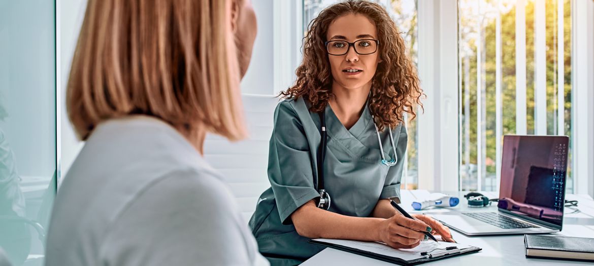 Doctor woman dressed in medical suit talking in office. Reception and consultation with a doctor.